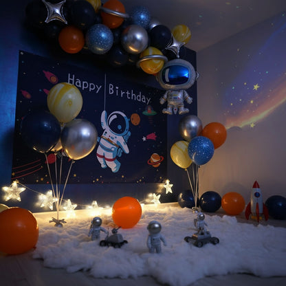 Space-themed birthday party setup with balloons, decorations, and toys on a dark background.