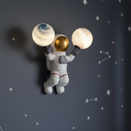 Decorative wall light shaped like an astronaut holding two planets against a starry background