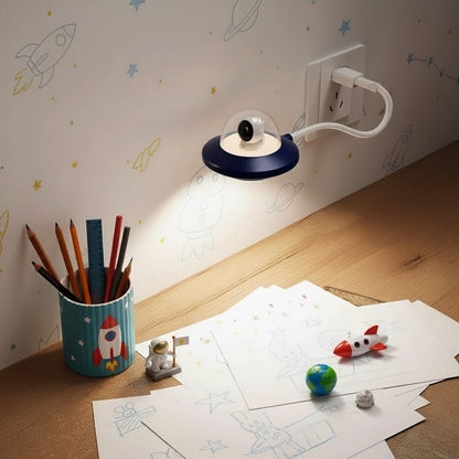 Children's desk with a lamp, pencils, and model rockets on a wooden surface.